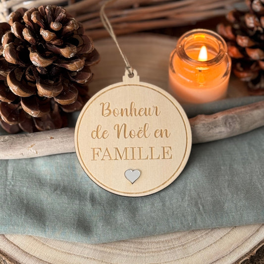 Boule de Noël en bois, avec la gravure "Bonheur de Noël en FAMILLE" , un petit coeur en dessous du texte en relief argent miroir